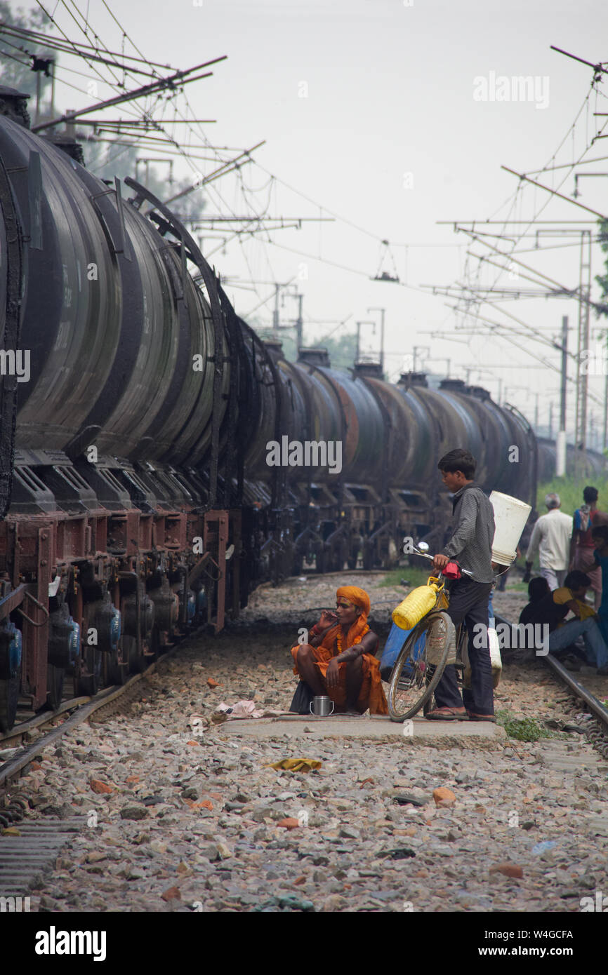 Freight train running on track and a group of people waiting to cross