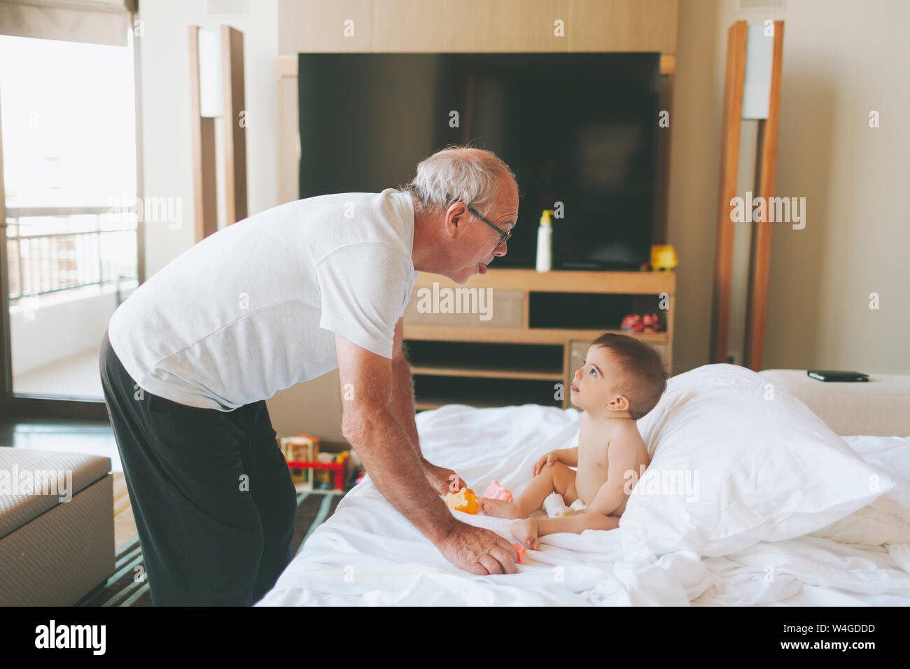 Grandfather playing with a baby at home sticking out tongue Stock Photo