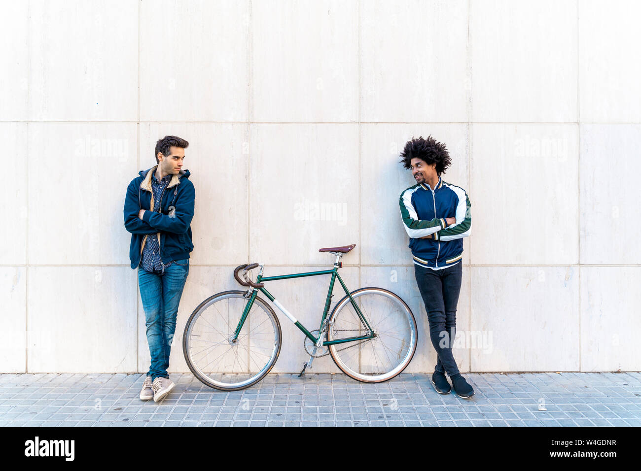 Two casual men with bicycle standing at a wall Stock Photo