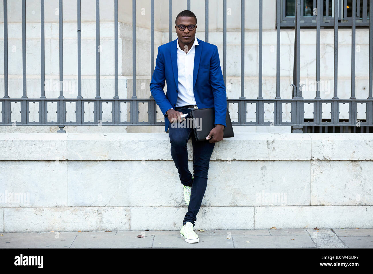 Young businessman wearing blue suit jacket and holding smartphone and  laptop bag Stock Photo - Alamy