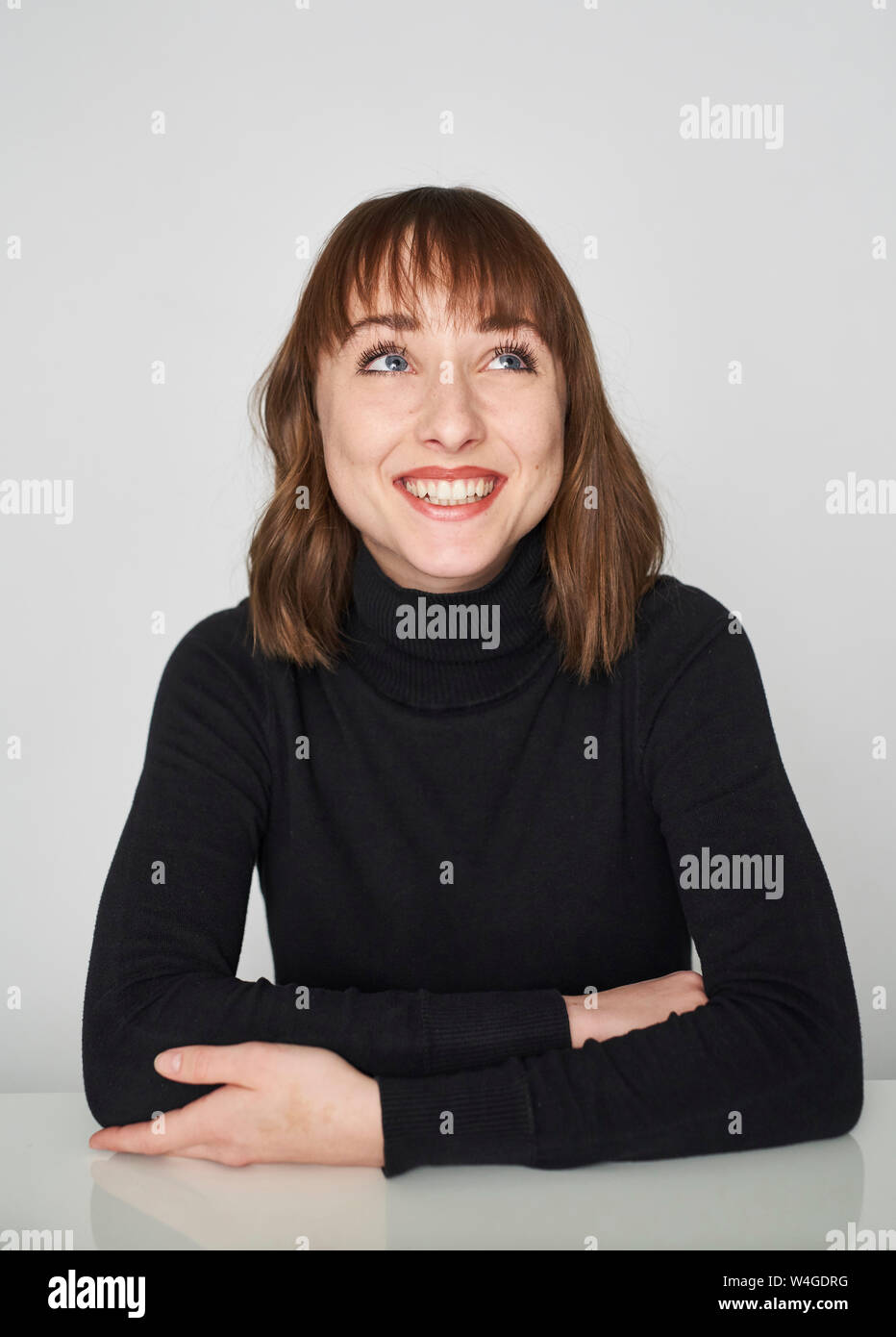 Portrait of smiling young woman wearing black turtleneck pullover looking up Stock Photo