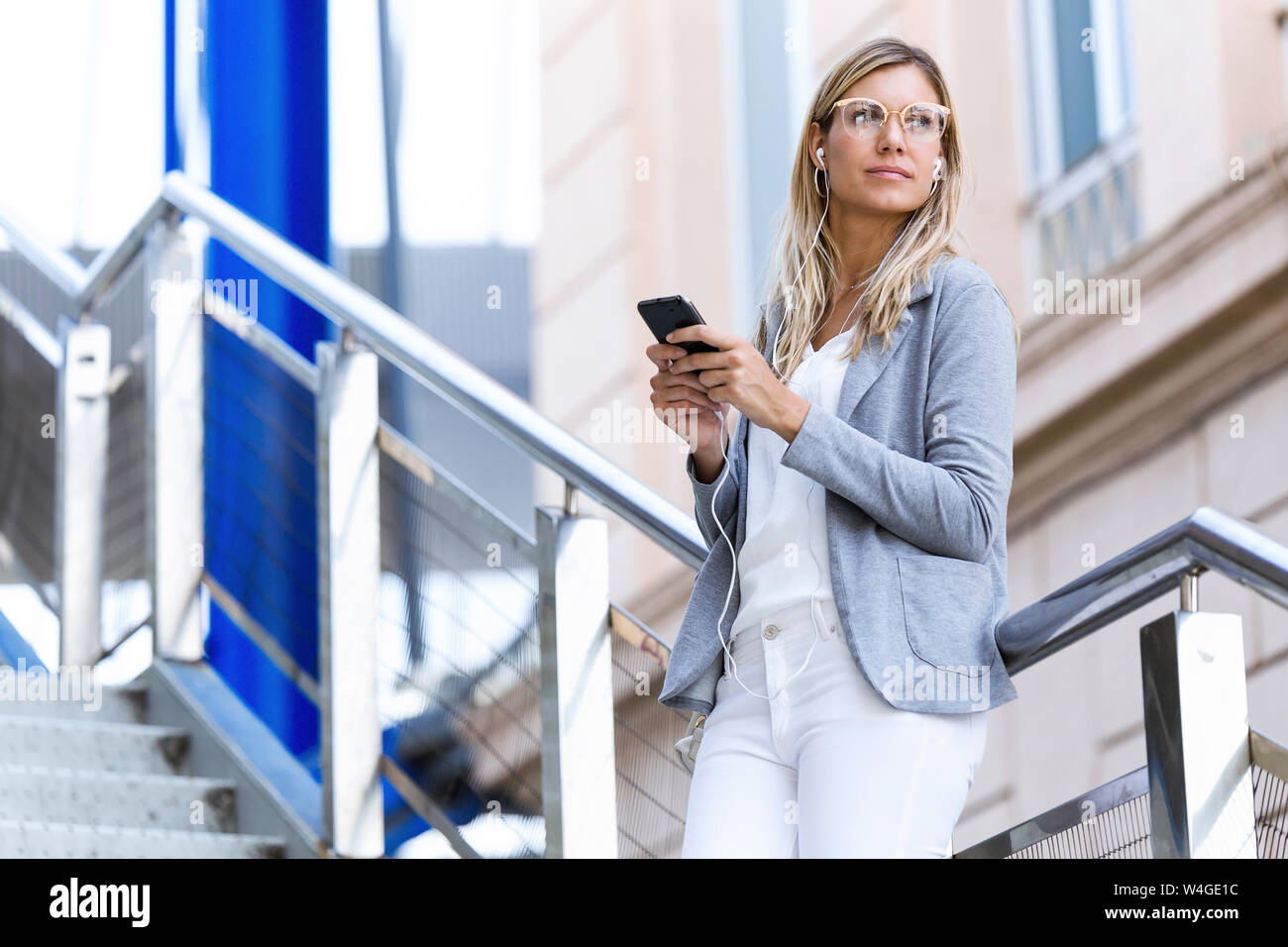 Young businesswoman texting with her mobile phone on stairs Stock Photo