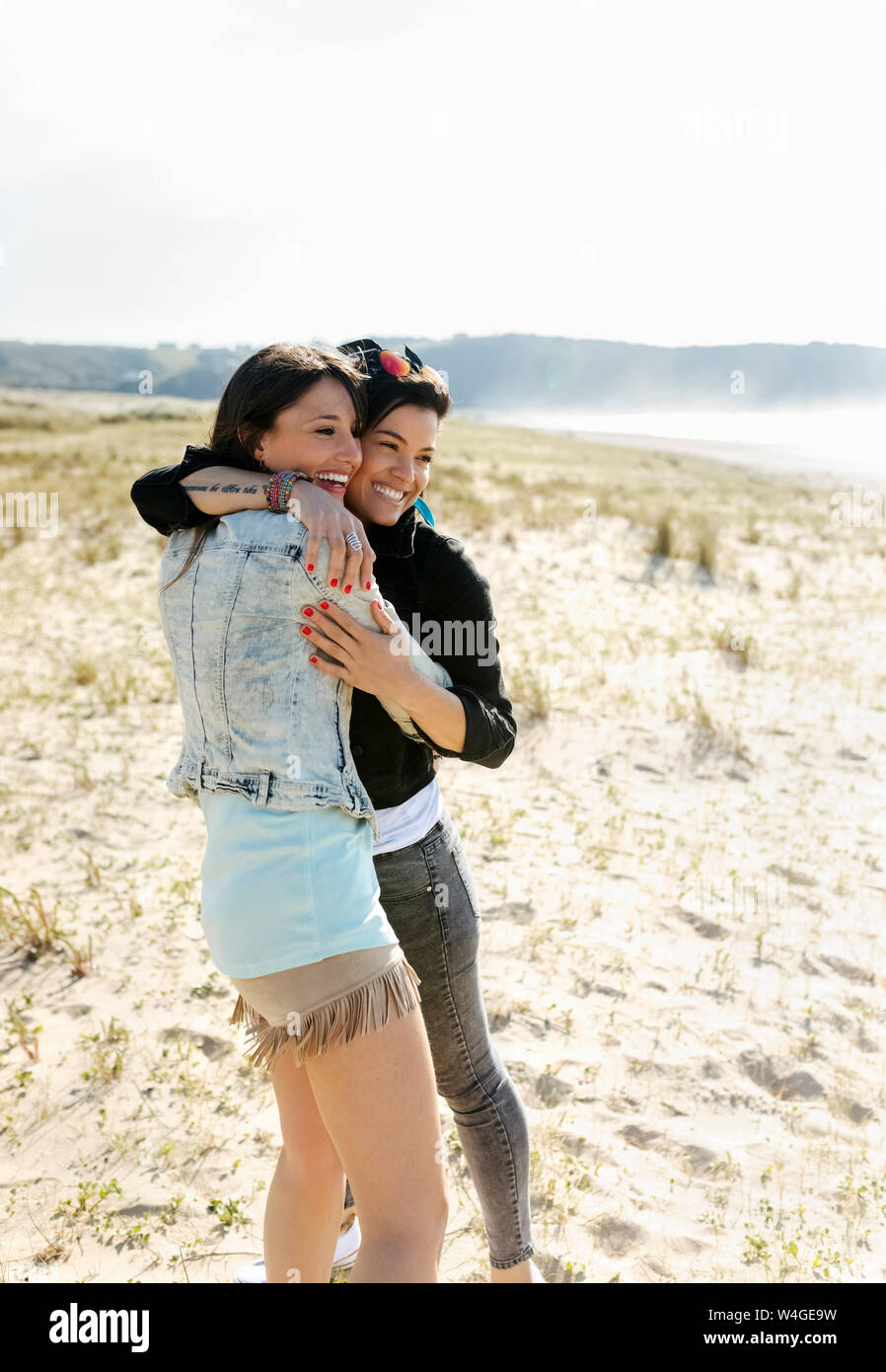 Two happy female friends hugging on the beach Stock Photo