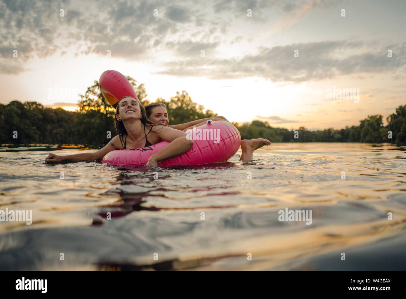 Friends having fun on a lake on a pink flamingo floating tire Stock Photo