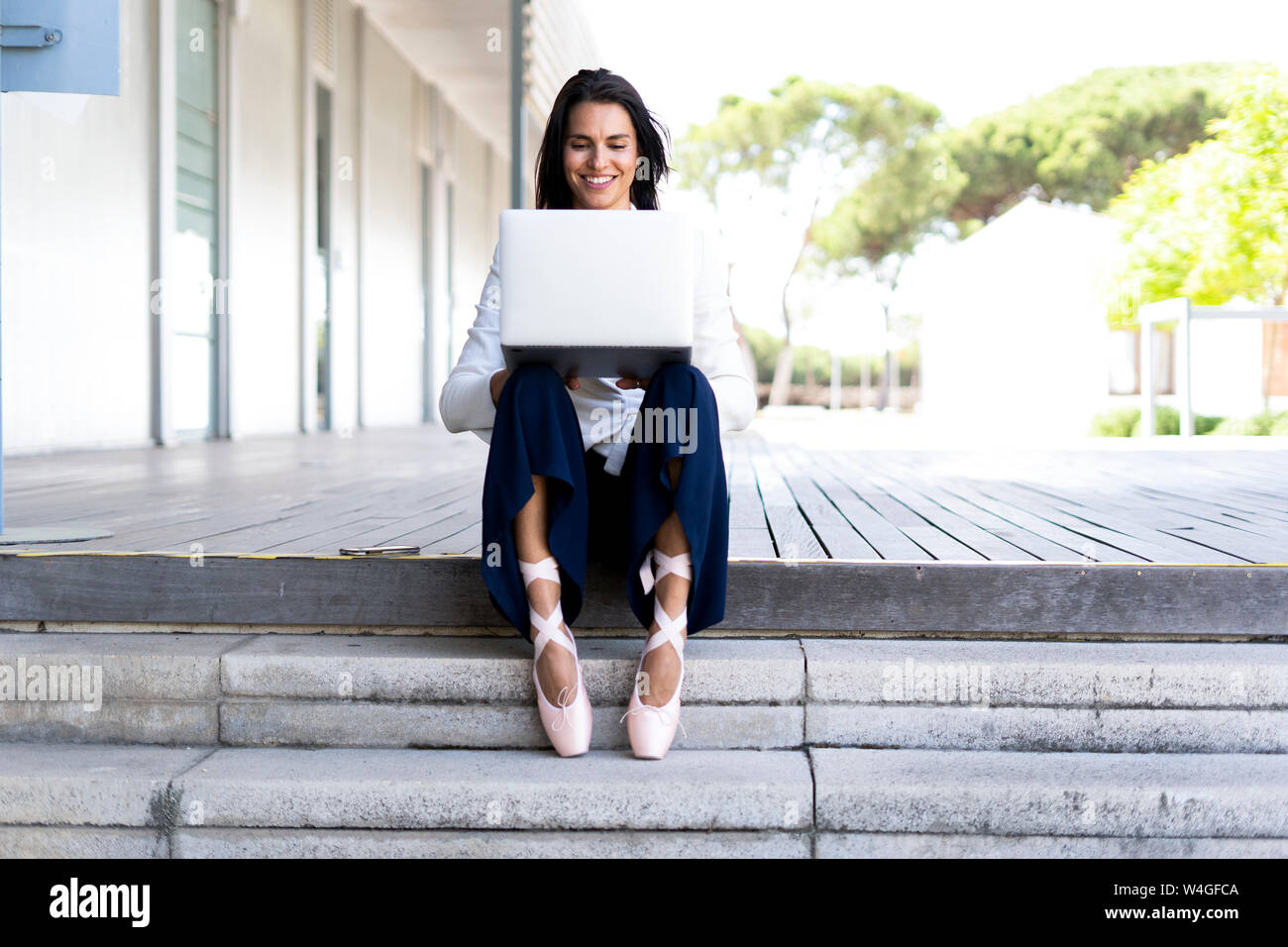 Female ballet dancer using laptop sitting on steps Stock Photo