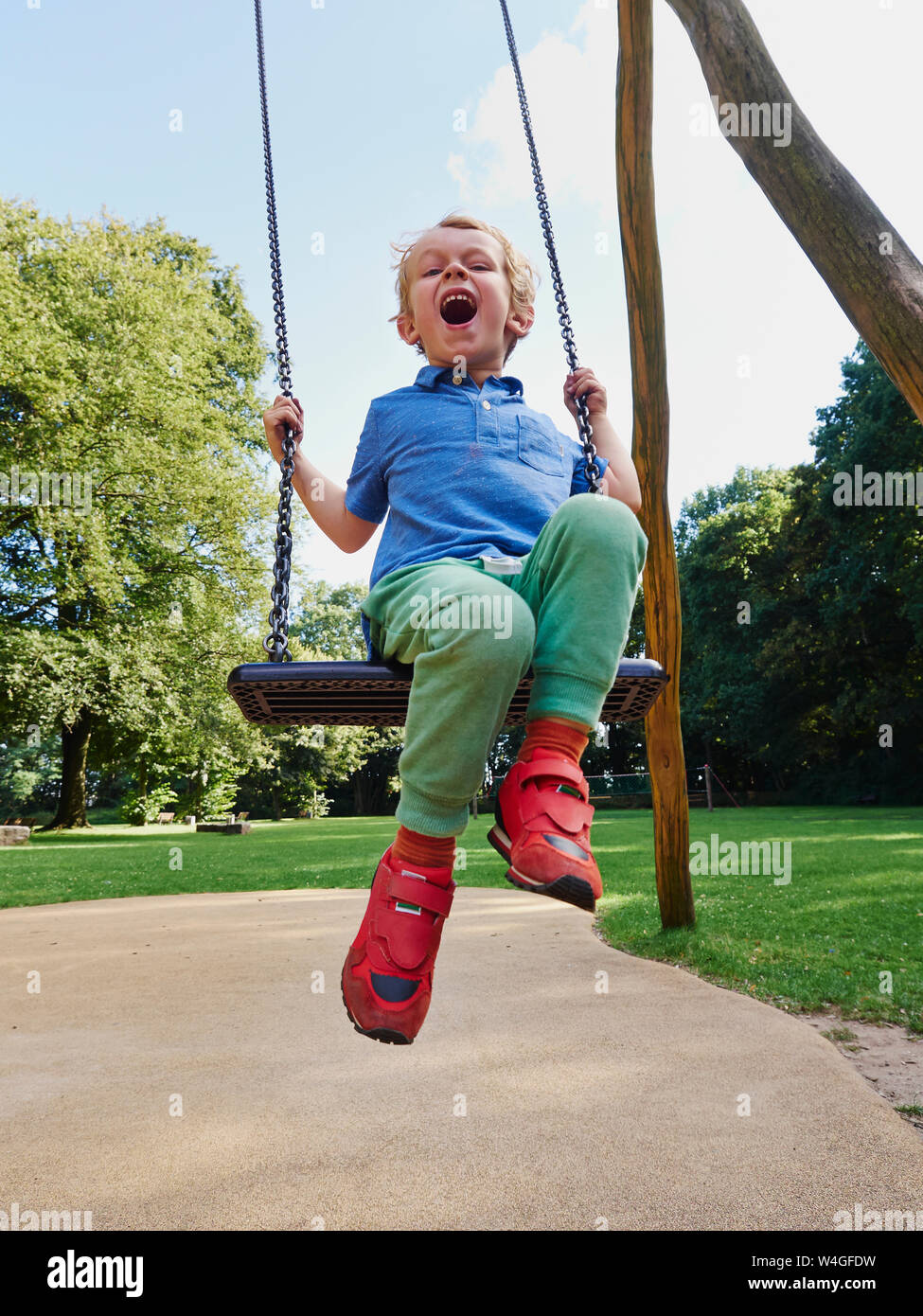 Portrait of screaming little boy on swing Stock Photo
