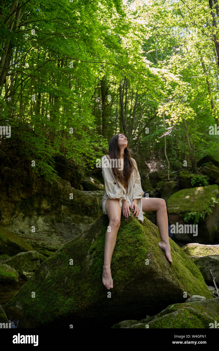 Young woman sitting on a rock in the forest, Garrotxa, Spain Stock Photo