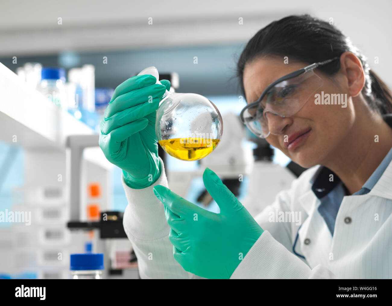 Biotech Research, Scientist swirling a chemical formula in a laboratory flask during a experiment Stock Photo