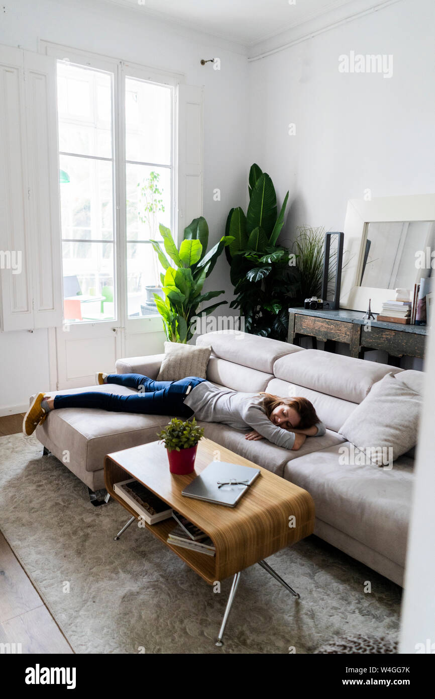 Young woman lying on the couch at home Stock Photo - Alamy