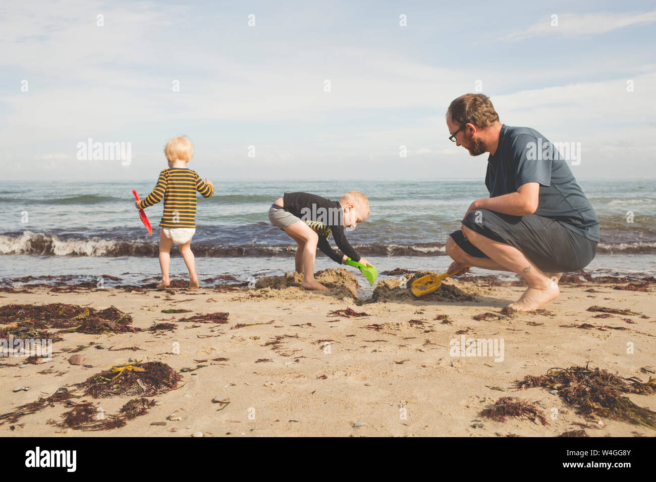 Father with two kids playing on the beach Stock Photo