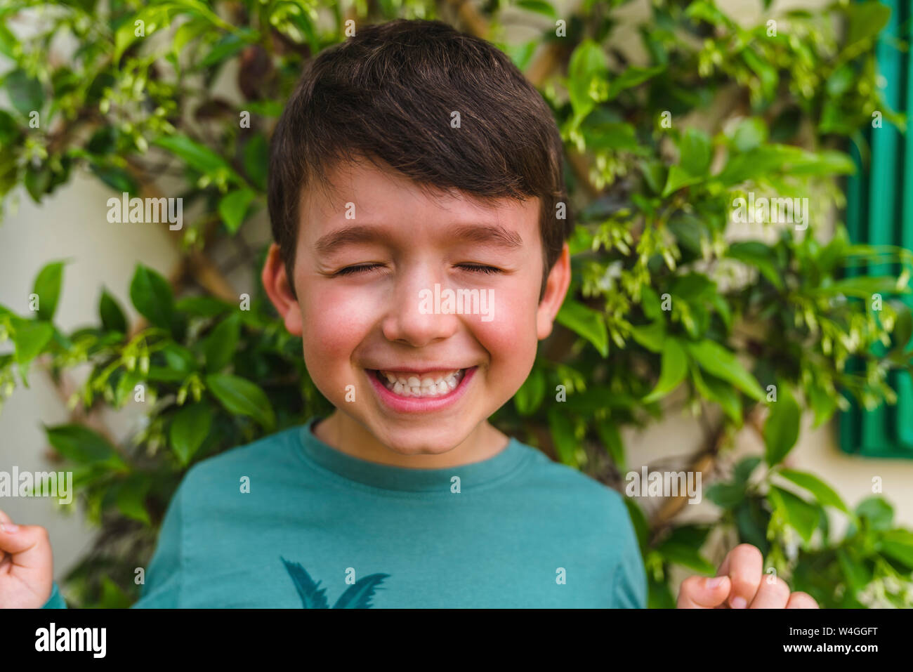 Portrait of grinning little boy on balcony with eyes closed Stock Photo