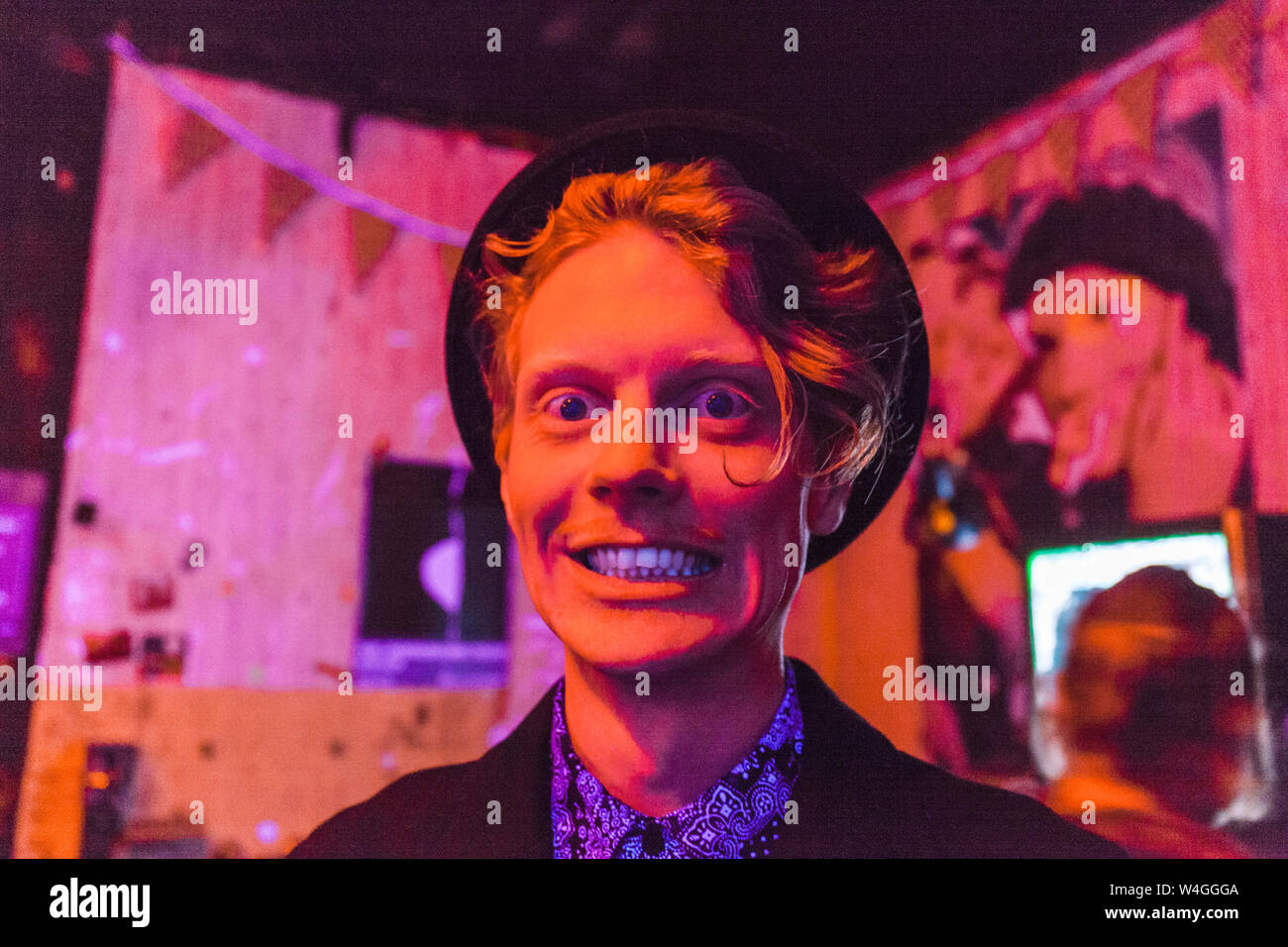 Young man wearing hat during psychedelic party, effects of light machine on a wall Stock Photo