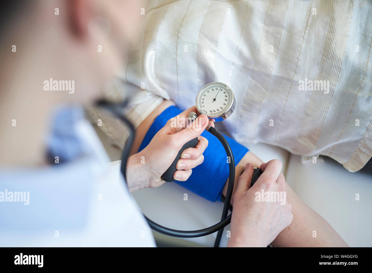 Doctor taking patient blood pressure hires stock photography and