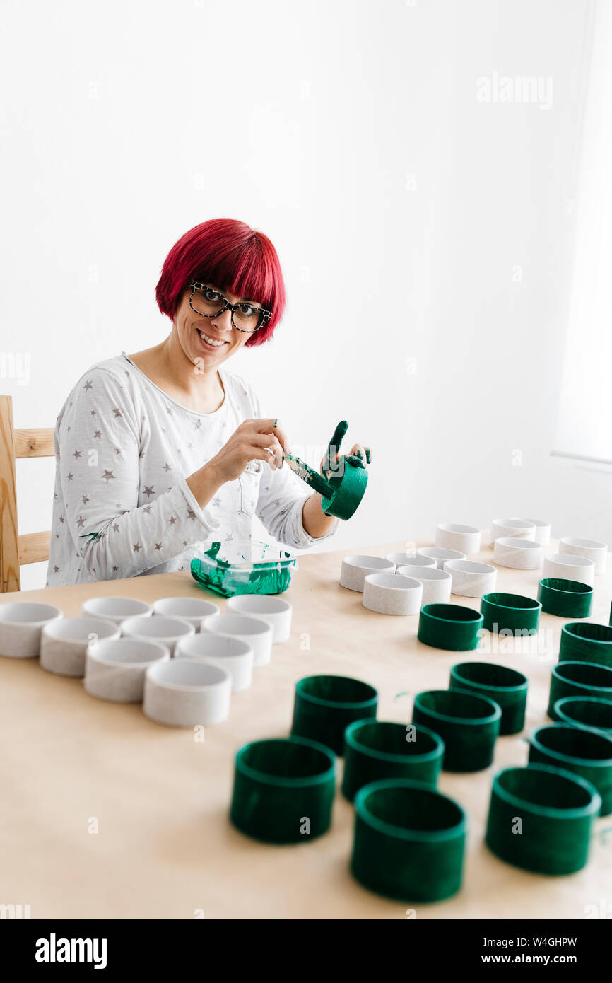 Woman painting a roll of cardboard with a green brush to make a Christmas tree Stock Photo