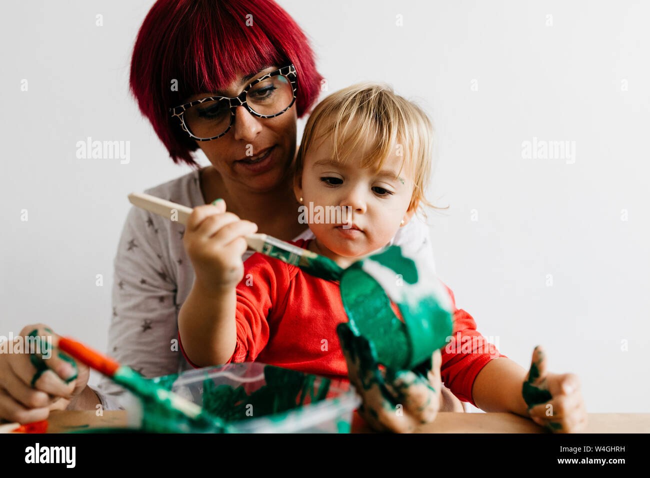 Mother and daughter doing crafts at home painting cardboard roll Stock Photo