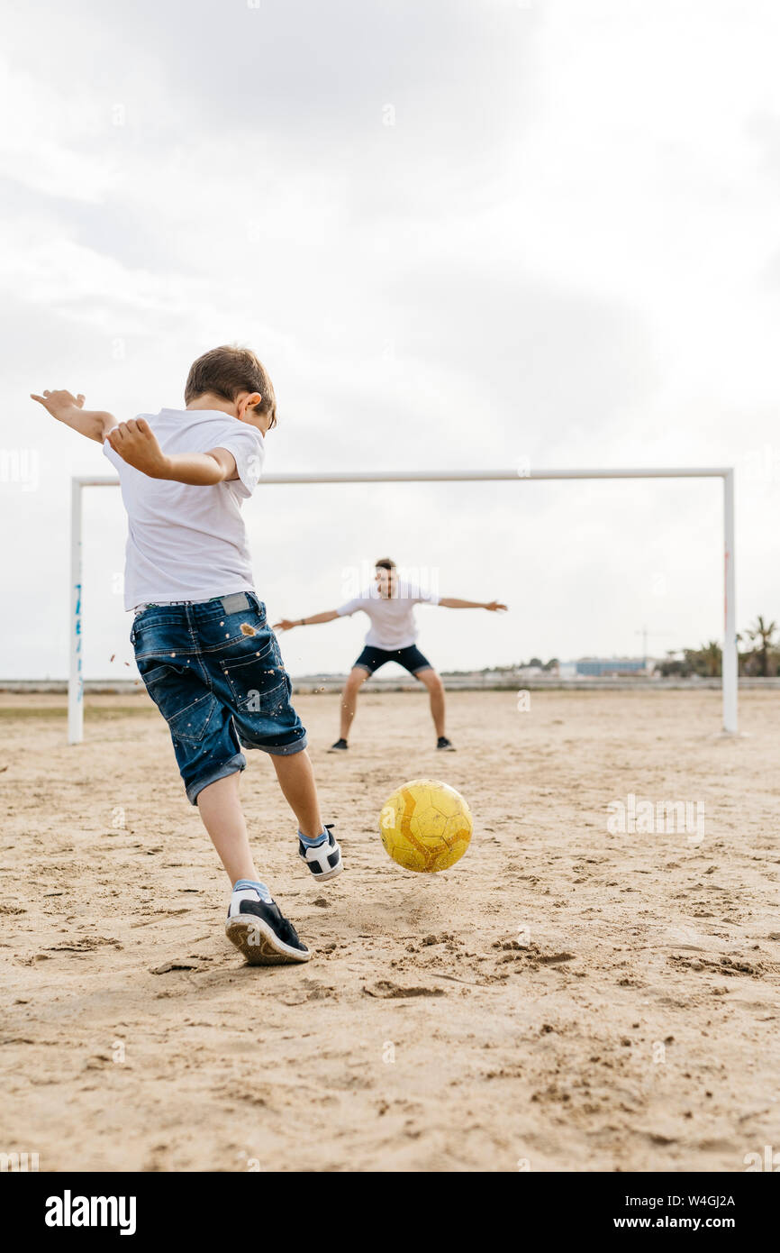 Man and boy playing soccer on the beach Stock Photo
