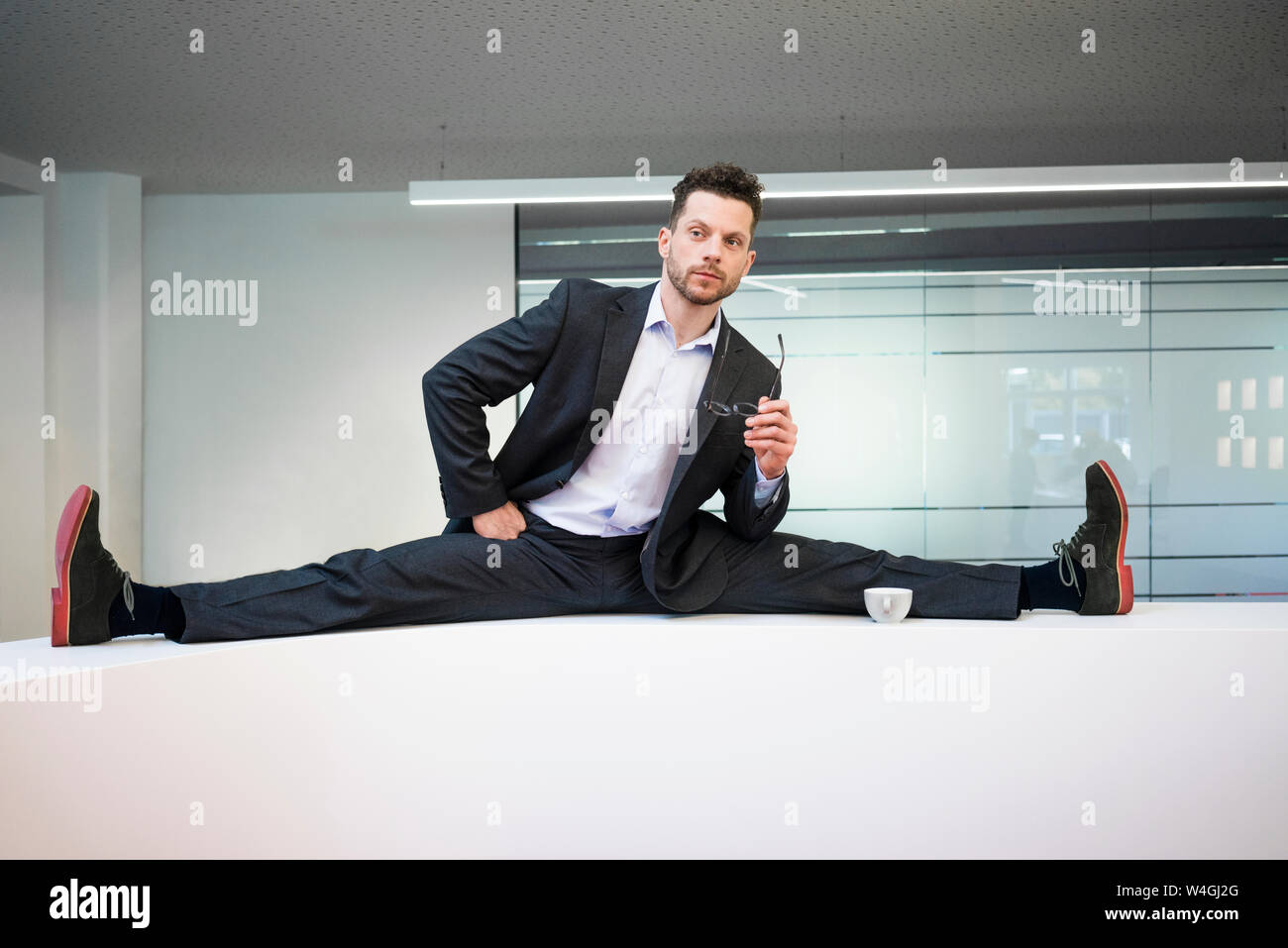 Businessman doing the splits on reception desk in office Stock Photo