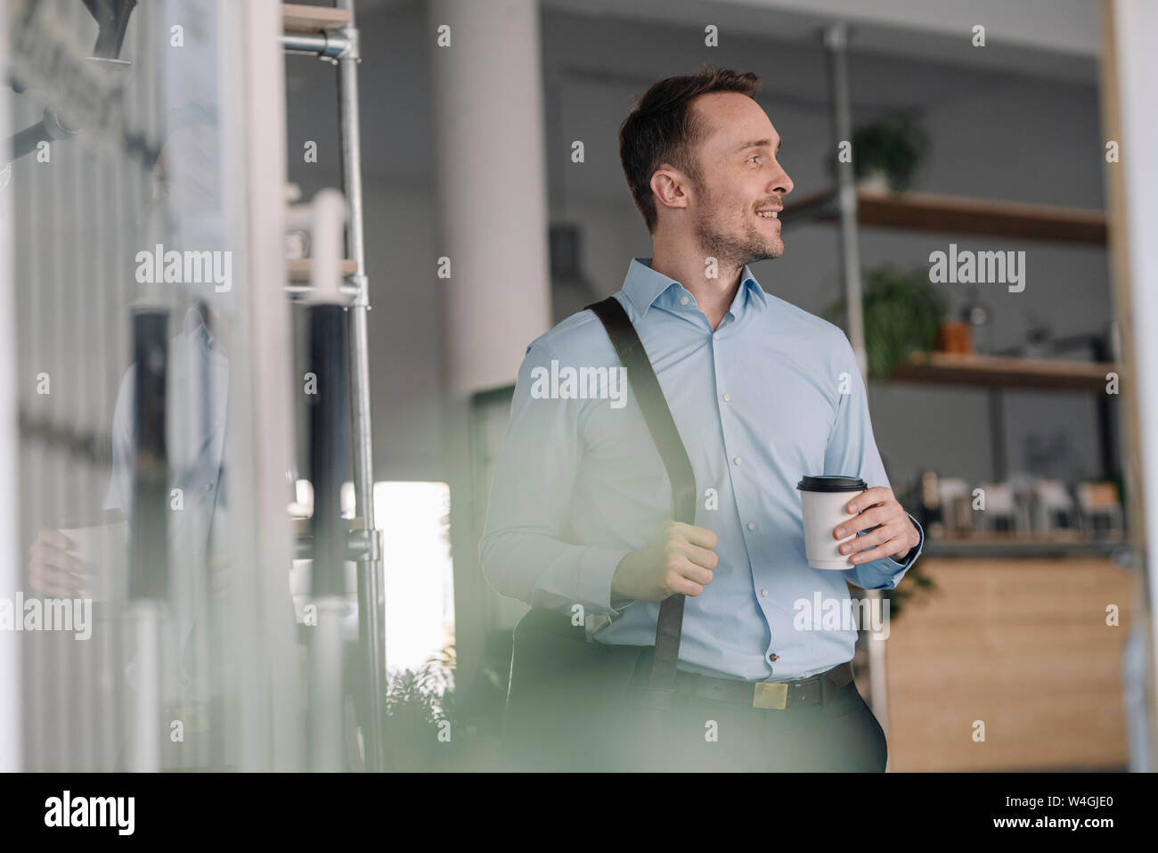 Businessman leaving coffee shope with take out coffee Stock Photo