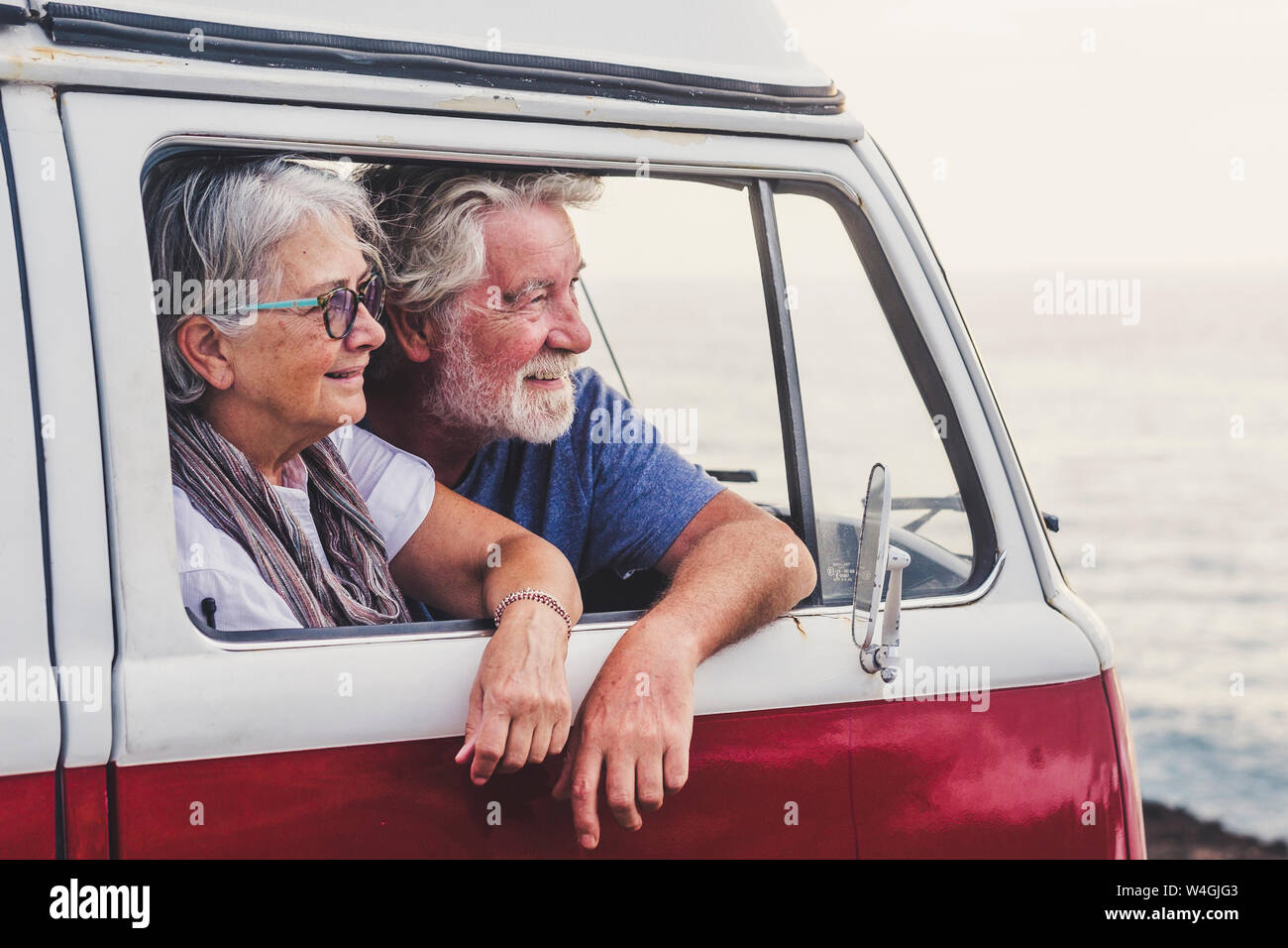 Senior couple traveling in a vintage van, looking at the sea Stock Photo