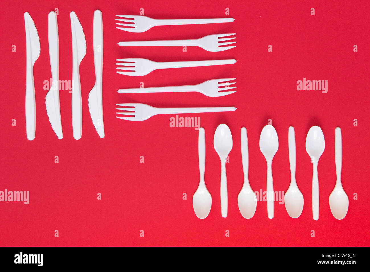 Plastic cutlery on red background Stock Photo Alamy