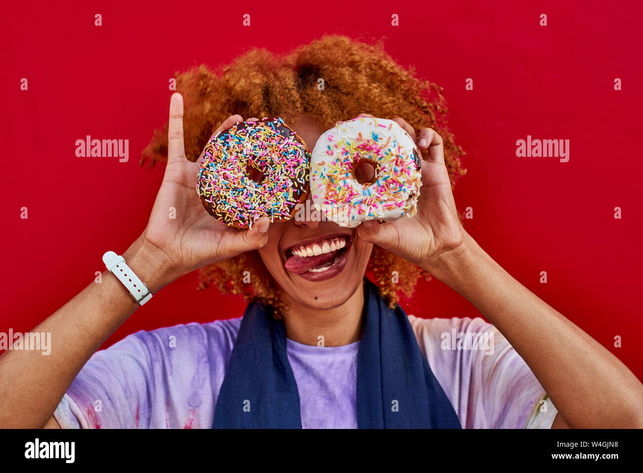 Playful woman holding two donuts in front of her eyes Stock Photo