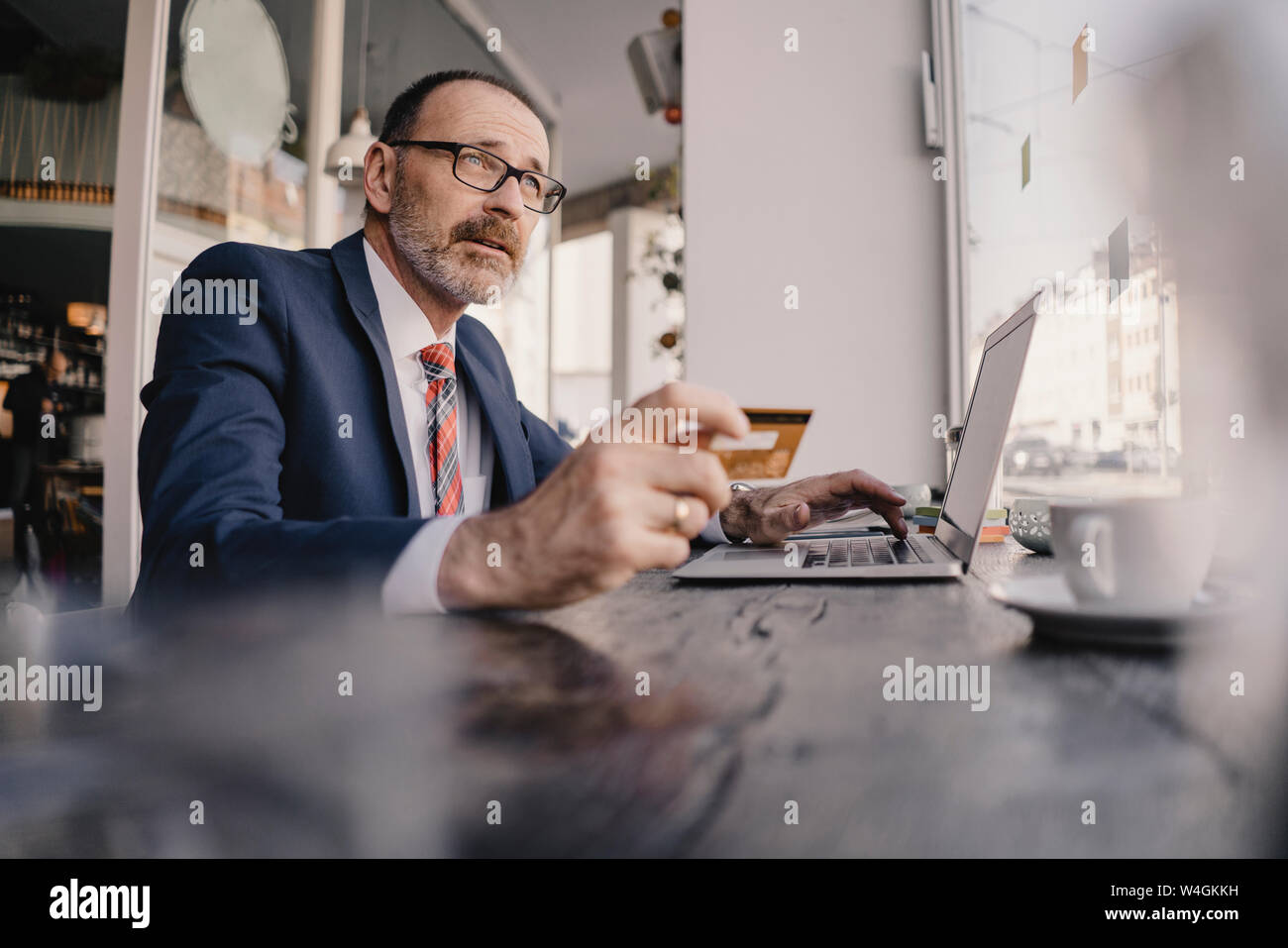 Mature businessman using laptop and credit card in a cafe Stock Photo