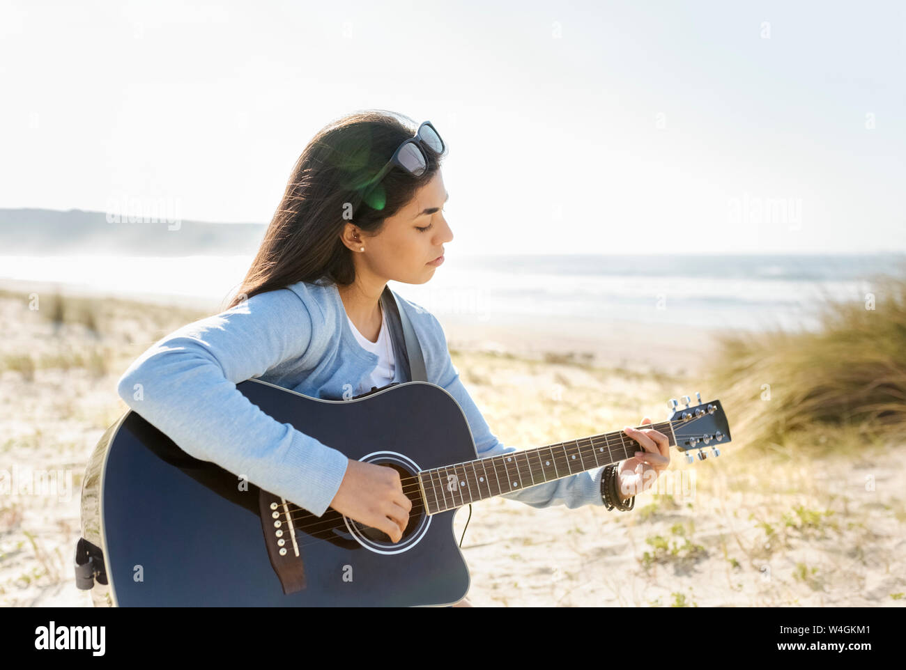 Young woman playing guitar on the beach Stock Photo
