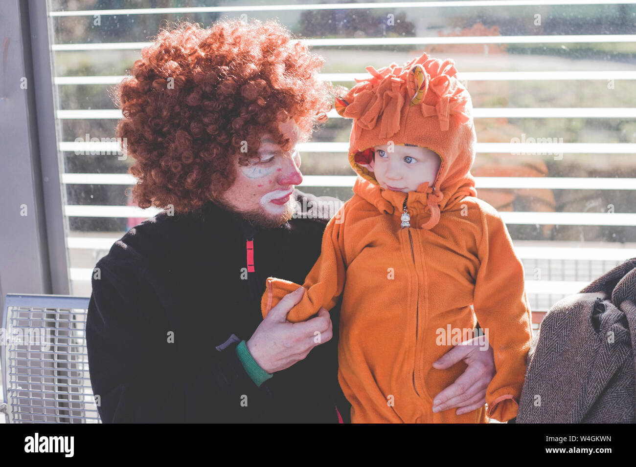 Man dressed up as a clown and little boy dressed up as lion baby at carnival Stock Photo