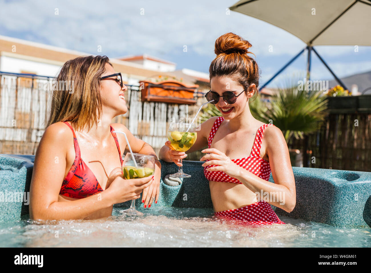 Two women having a drink in a jacuzzi Stock Photo