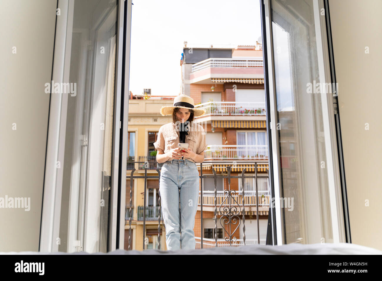 Young woman on balcony in the city using cell phone Stock Photo