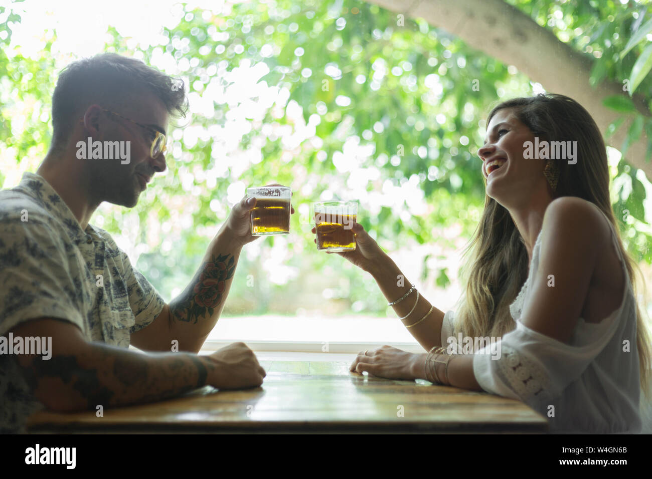 Happy young couple clinking beer glasses at the table of a restaurant Stock Photo