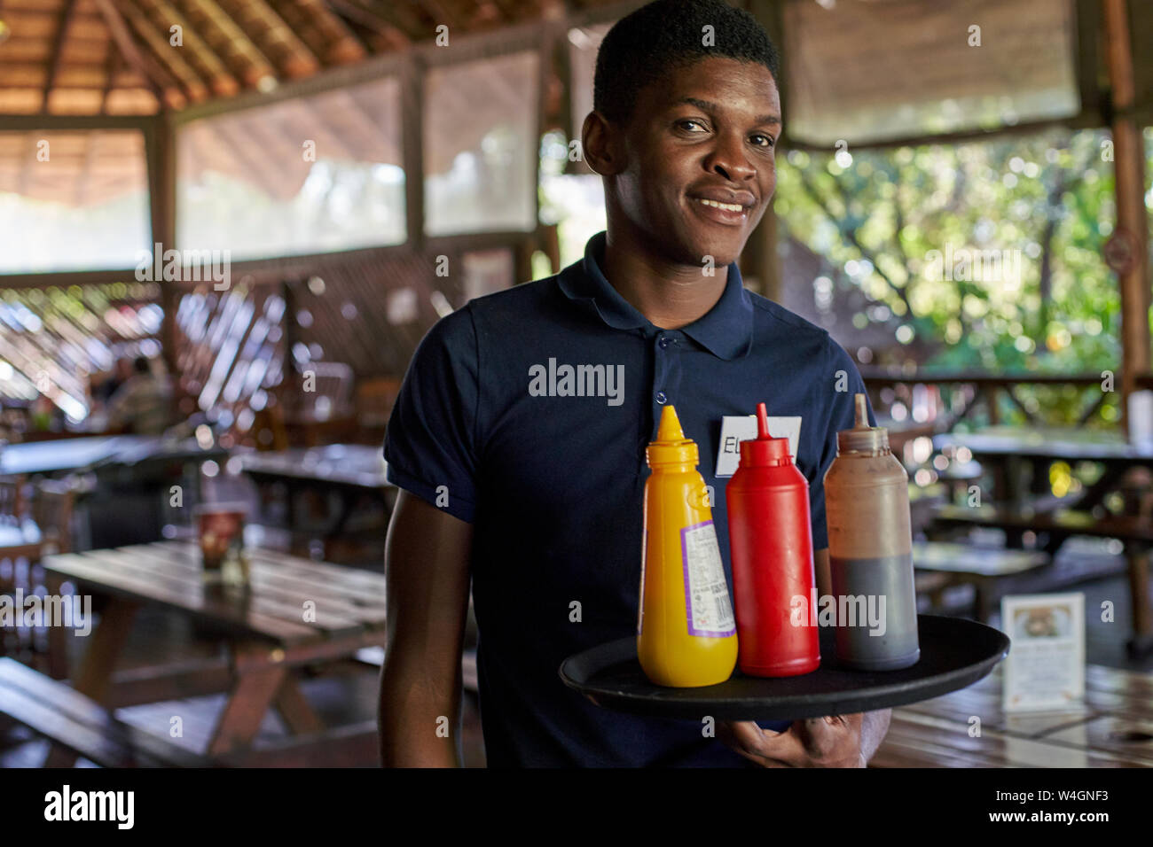 Young waiter serving sauces in bottles in a restaurant, South Africa Stock Photo