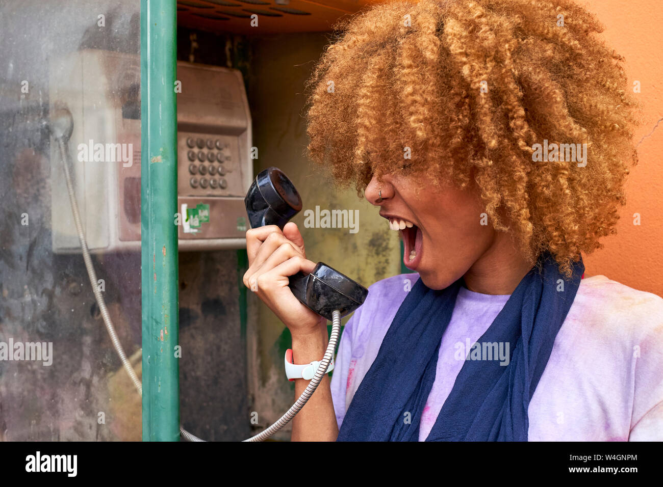 Woman yelling into old-fashioned telephone receiver Stock Photo