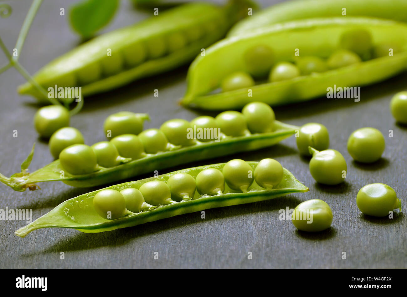 Fresh pods of peas on dark wooden table, close up Stock Photo