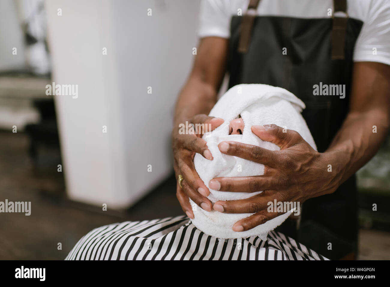Barber wiping customer's face with hot towel in barber shop Stock Photo