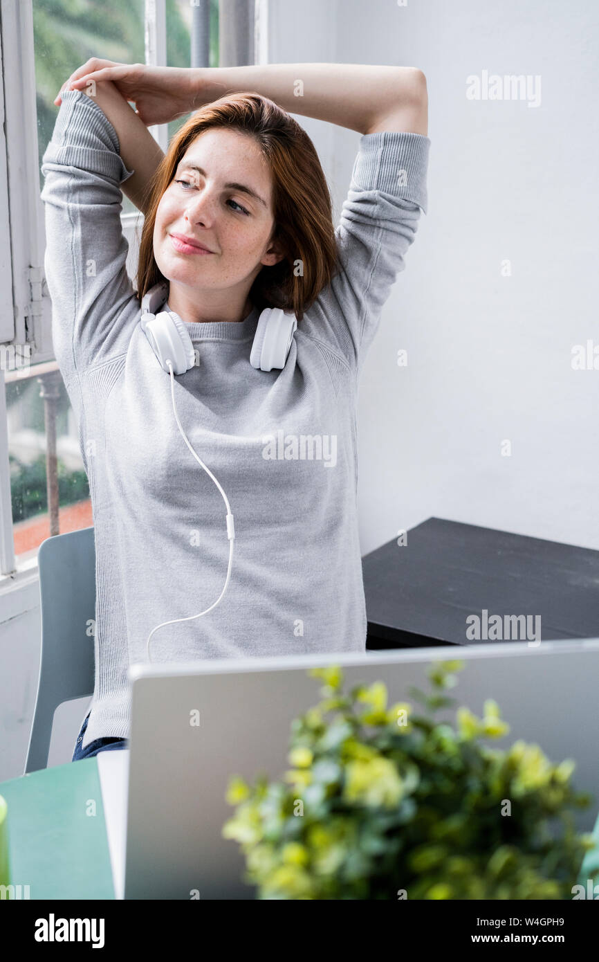 Young woman stting at table at home with laptop Stock Photo