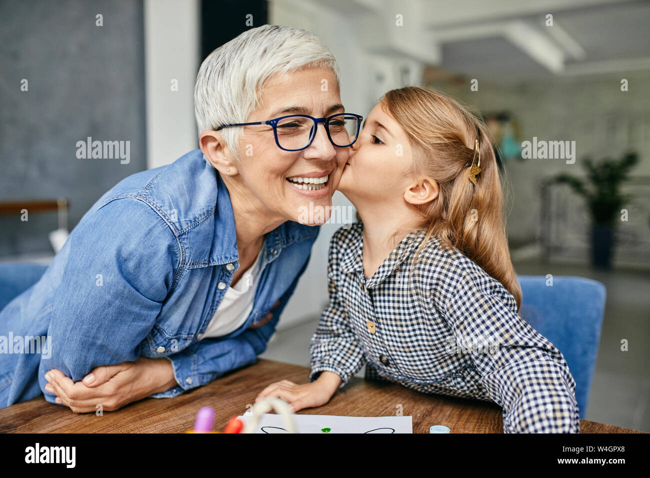 Grandduaf´ghter kissing grandmother, painting colouring book with her Stock Photo