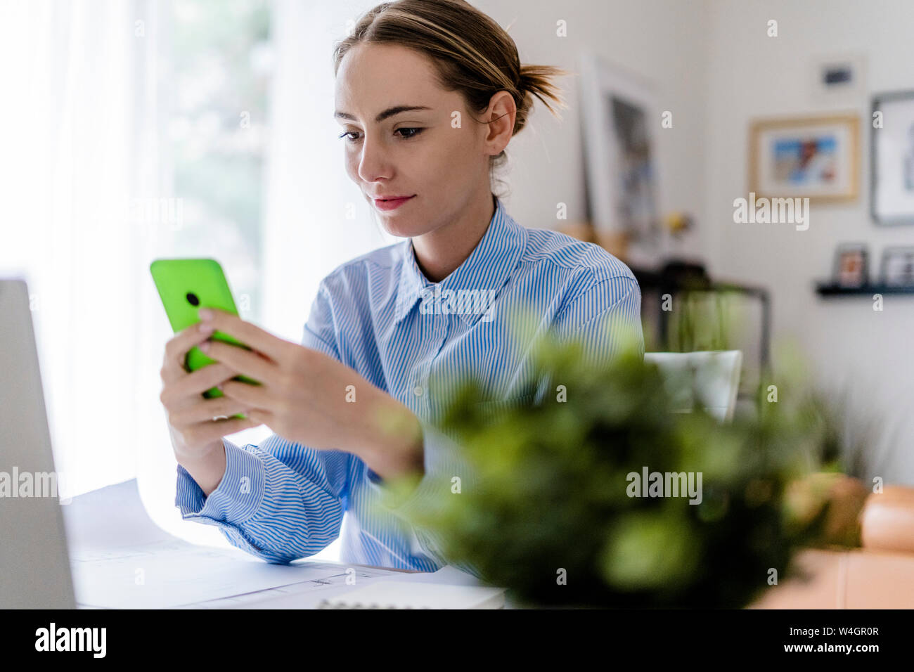 Woman in office using cell phone at table Stock Photo