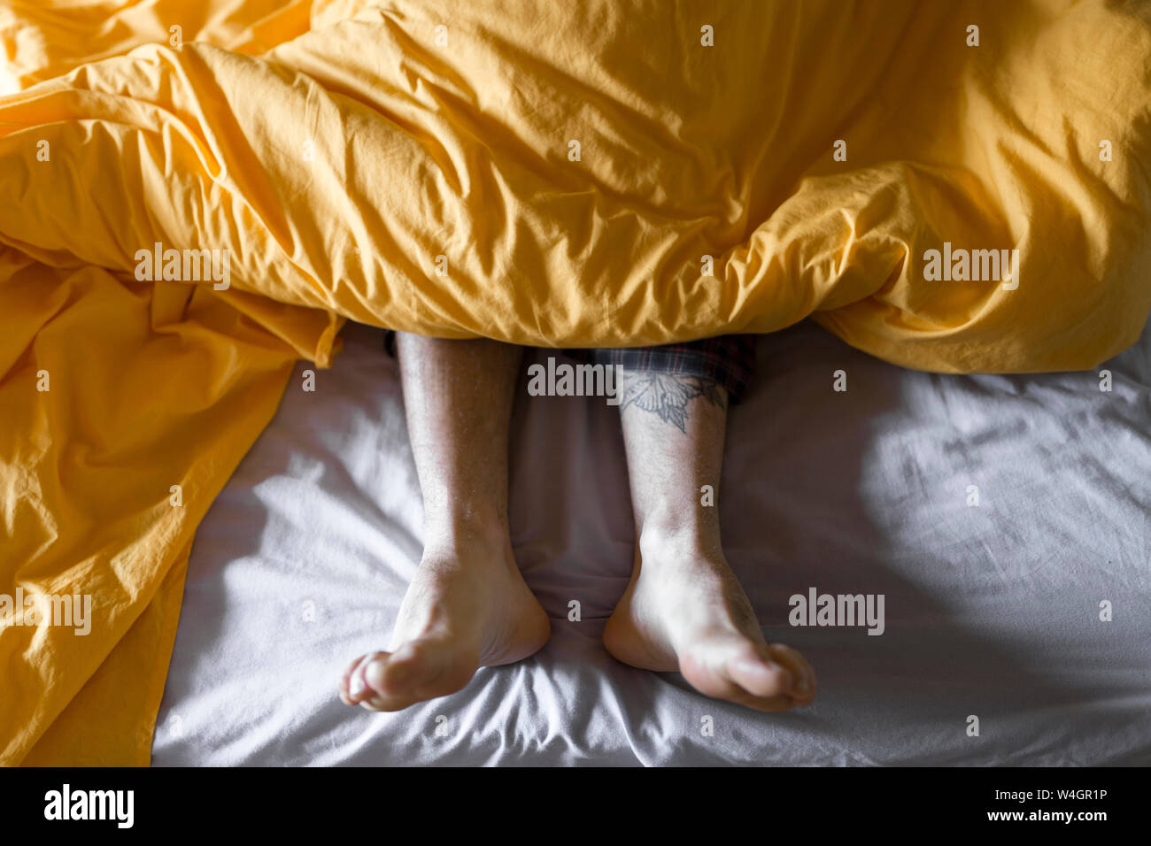 Tattooed man lying in bed Stock Photo