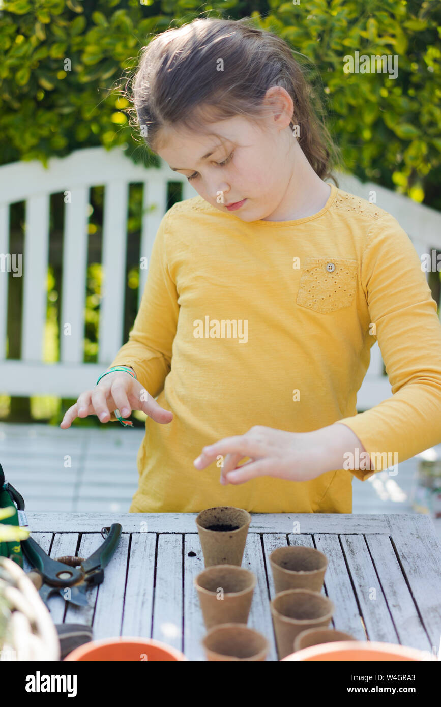 Girl with nursery pots on garden table Stock Photo