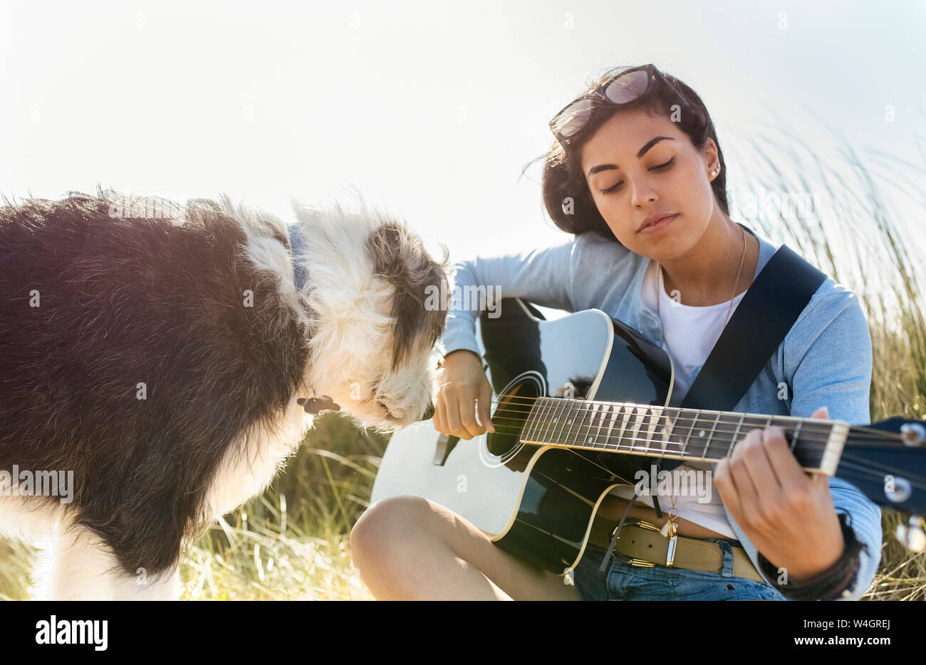 Young woman with dog playing guitar on the beach Stock Photo