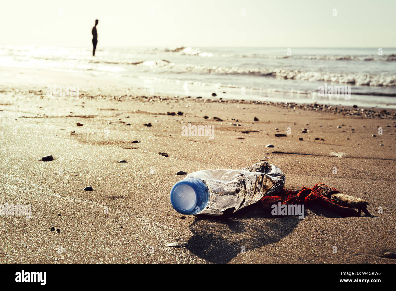 plastic bottle and trash lying on the shore of the beach and polluting the sea and the marine life, concept of pollution control of the oceans by plas Stock Photo