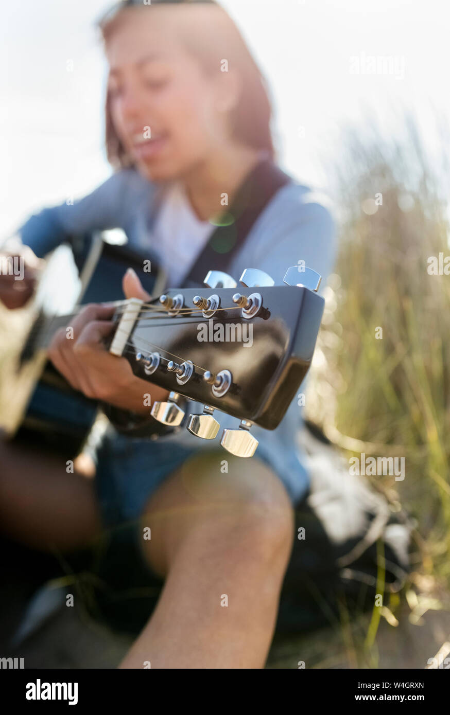 Close-up of young woman singing and playing guitar on the beach Stock Photo