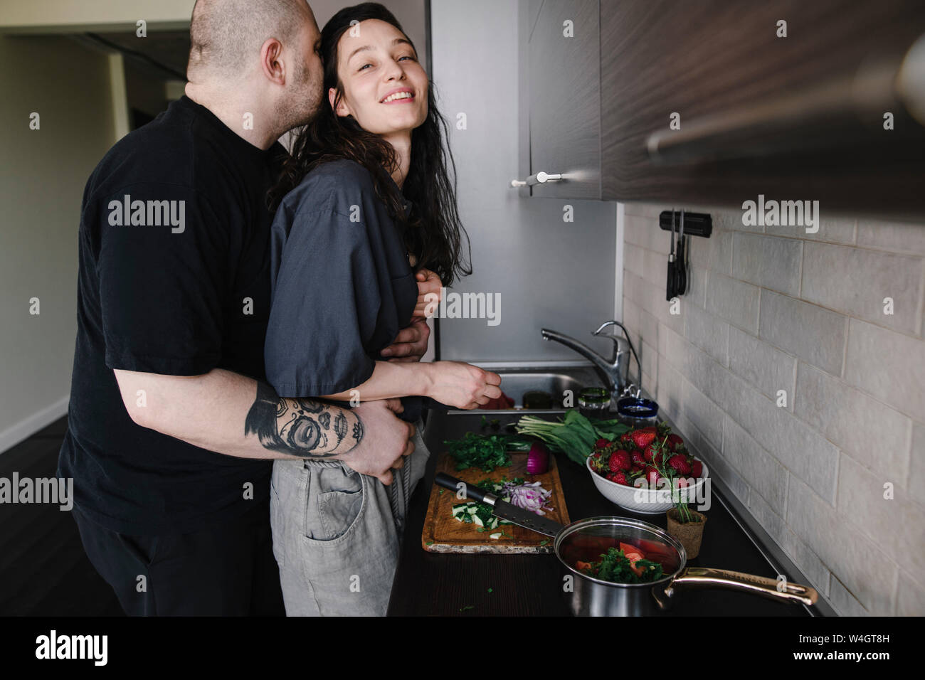 Man hugging and kissing woman in the kitchen Stock Photo