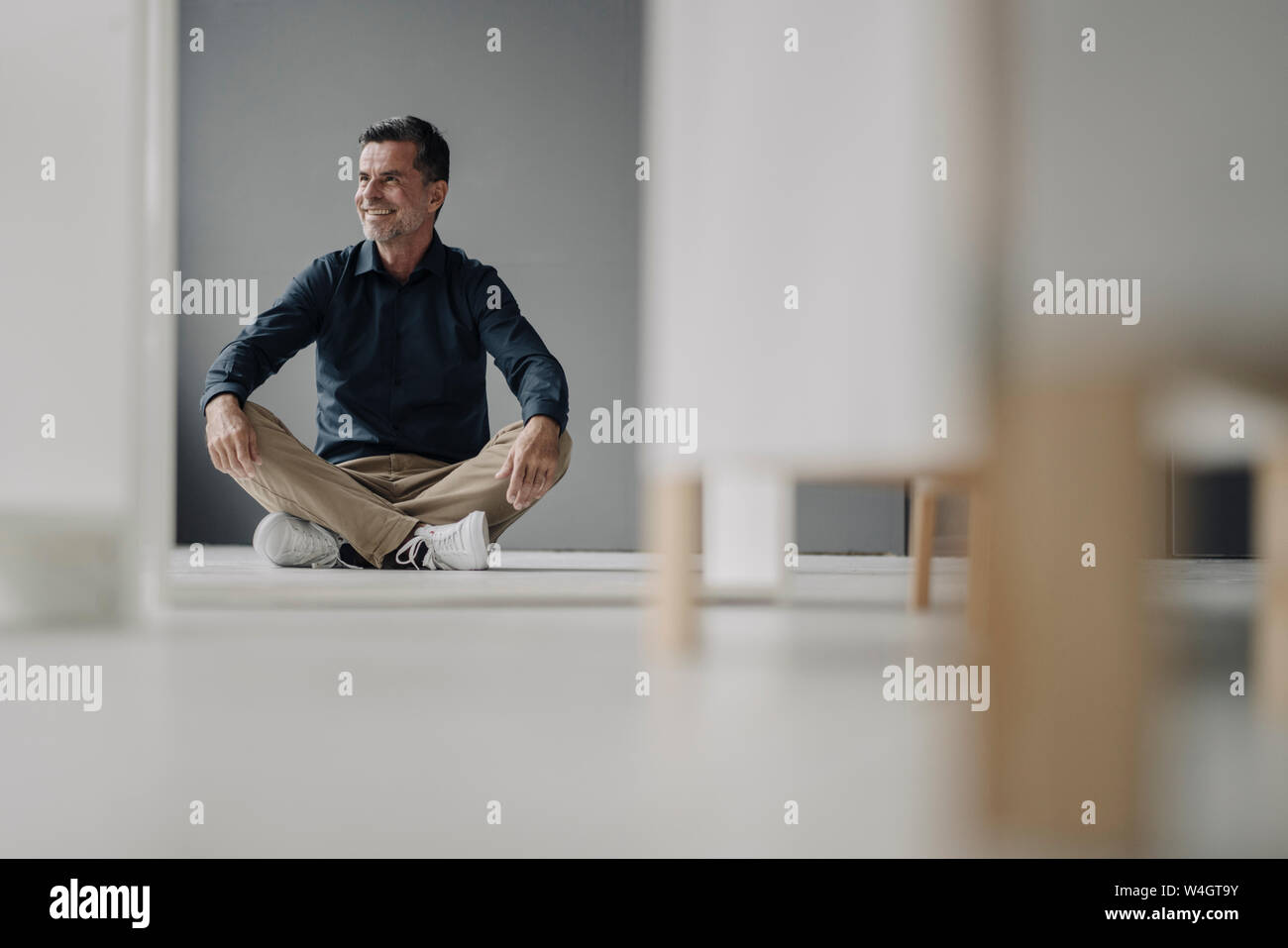 Smiling mature businessman sitting on the floor Stock Photo - Alamy