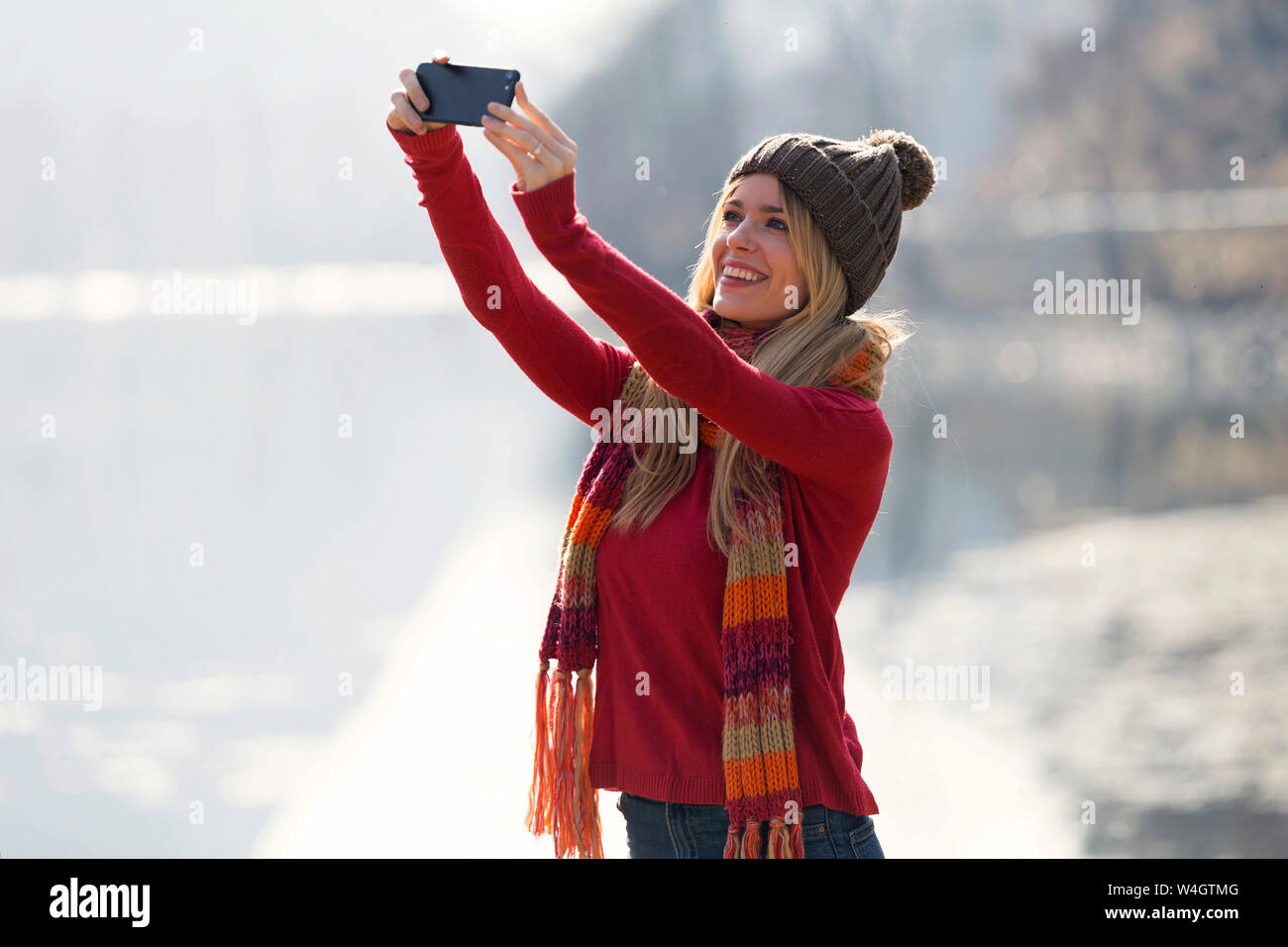 Young blond woman taking a selfie at a lake in winter Stock Photo