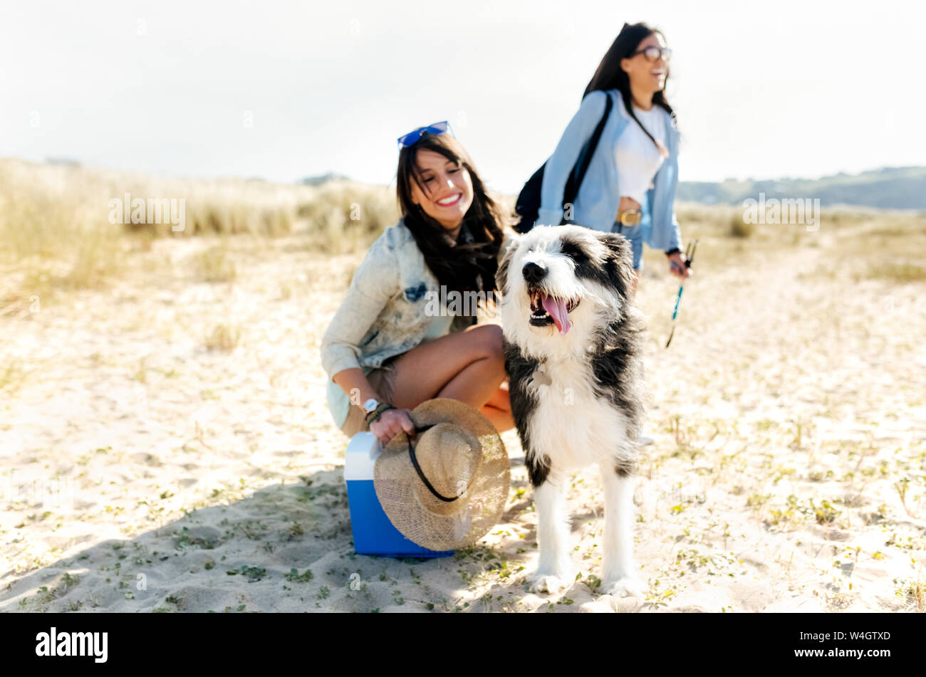 Two happy women with dog on the beach Stock Photo