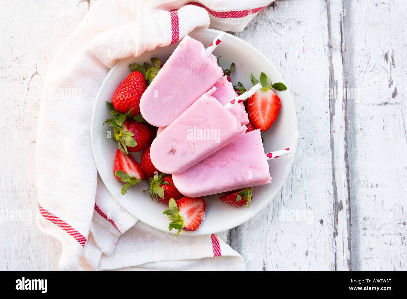 Homemade strawberry yogurt ice lollies with fresh strawberries in a