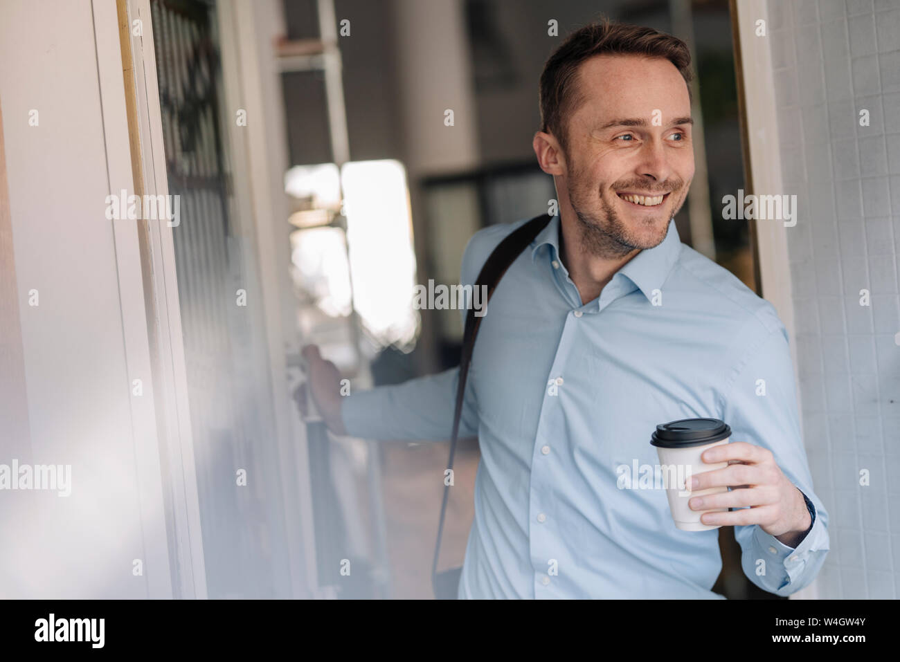 Businessman leaving coffee shope with take out coffee Stock Photo