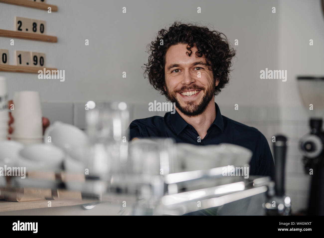 Proud coffee shop owner standing behind counter Stock Photo